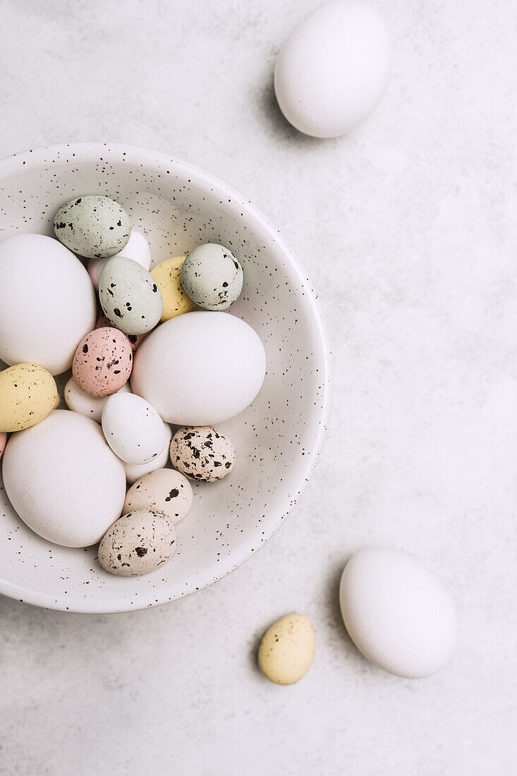 From above still life of beautiful painted Easter eggs over white table background