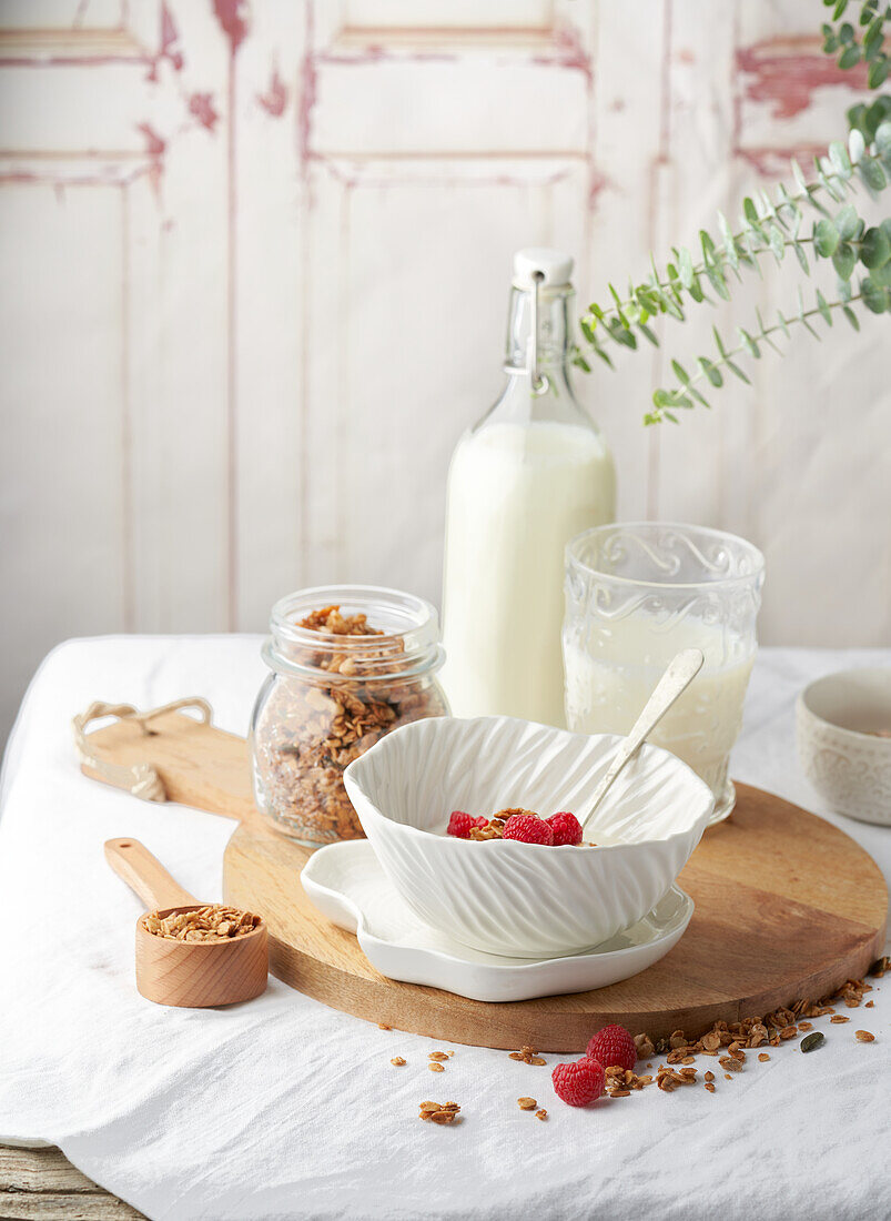 Leckeres Müsli mit einer Flasche frischer Milch zum Frühstück auf einem Holzbrett serviert