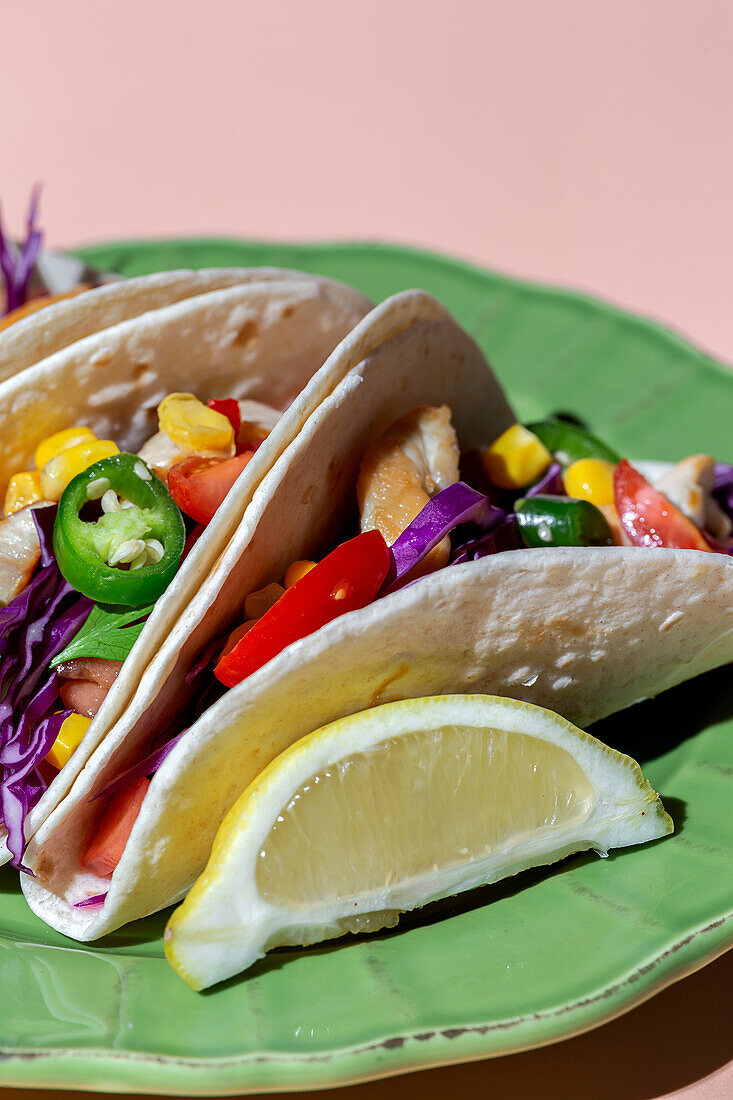 Homemade Mexican Tacos with fresh vegetables and chicken with strong light on pink background. Healthy food. Typical Mexican