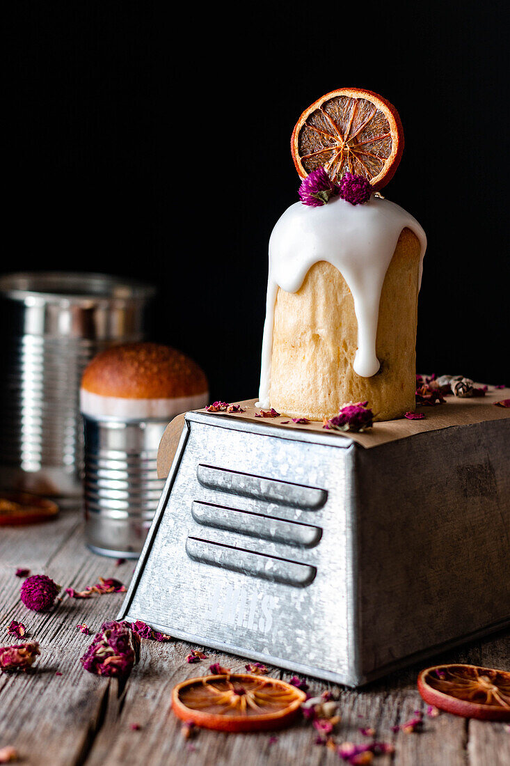 Several delicious homemade kulichs poured with sweet glaze and decorated with pieces of dry orange and flowers on wooden table