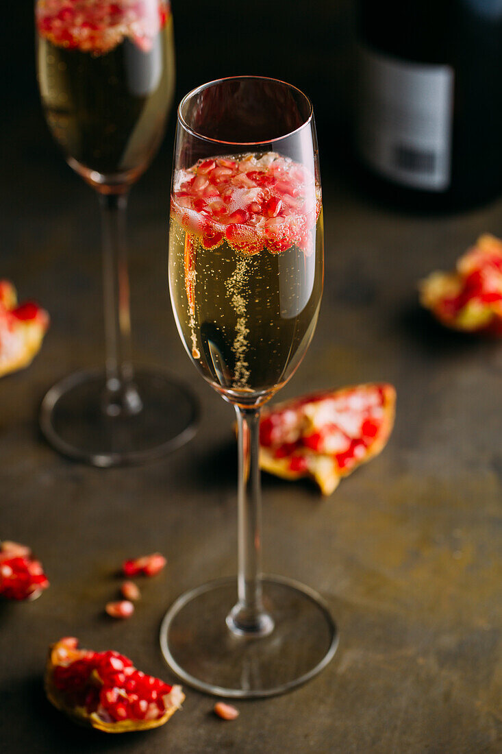 Still life composition of champagne cocktail with pomegranate on a rustic surface