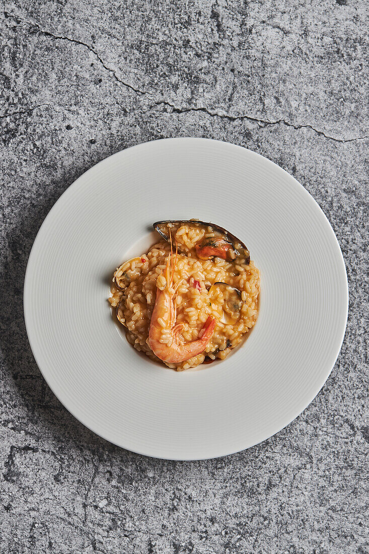 From above of appetizing rice with assorted seafood served on plate on table in restaurant