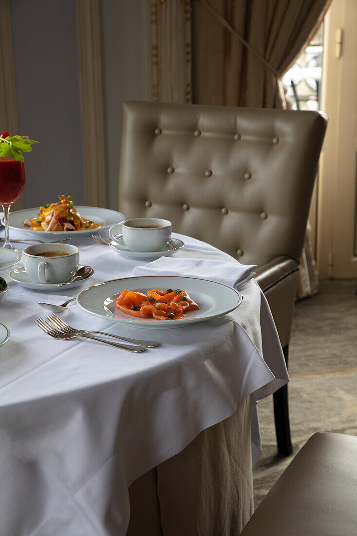 Various colorful dishes and juices served on round table during breakfast in elegant hotel restaurant in sunny morning