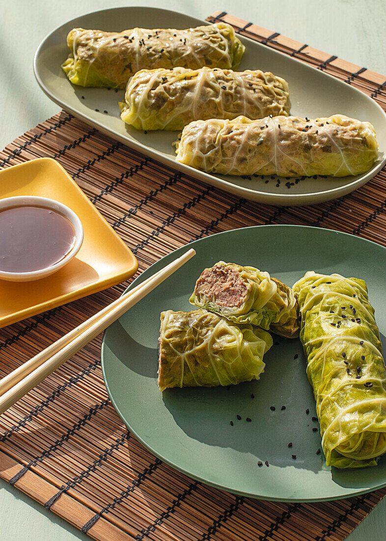 Cabbage spring rolls served on bamboo place mat near chopsticks