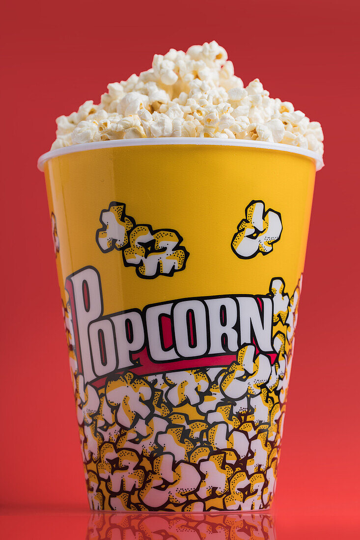 Bowl full of popcorn on a red background