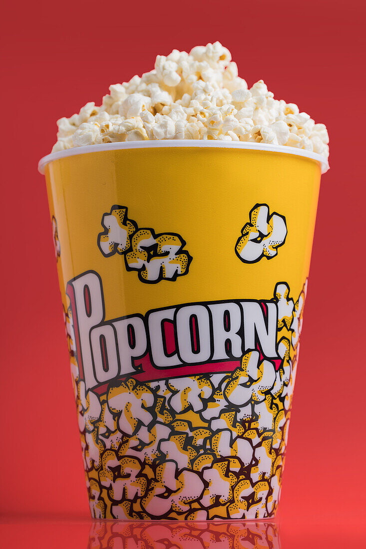Schale mit Popcorn auf rotem Hintergrund