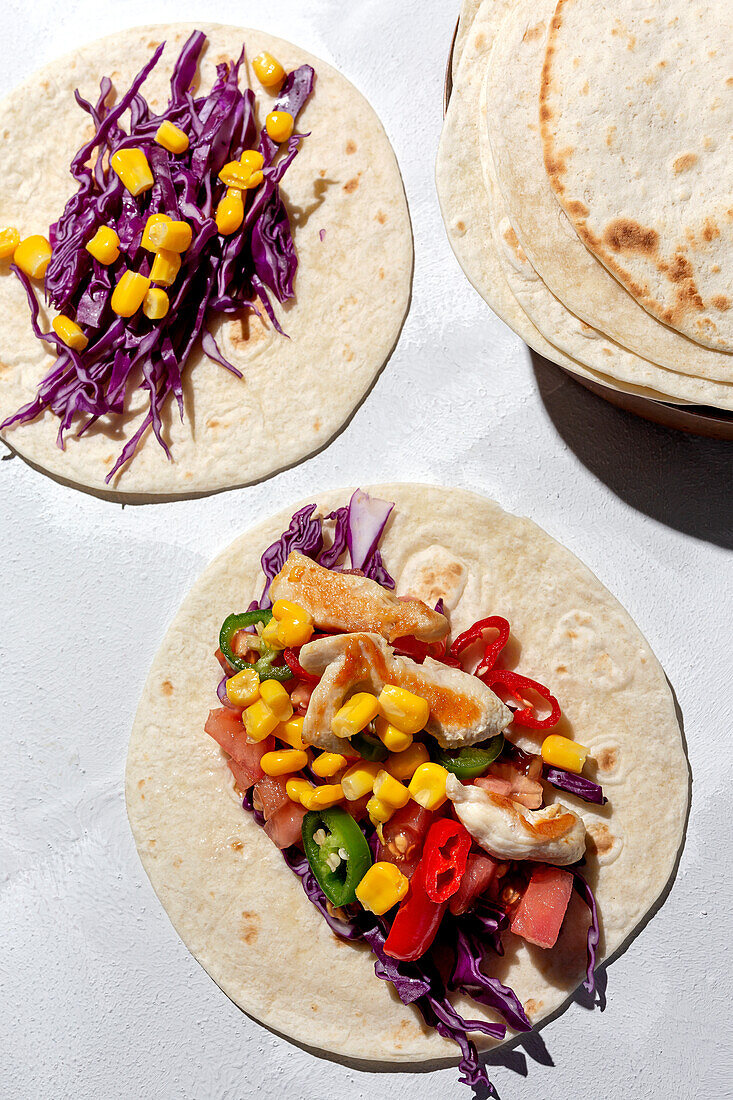 Hausgemachte mexikanische Tacos mit frischem Gemüse und Hühnchen mit starkem Licht auf weißem Hintergrund. Gesundes Essen. Typisch mexikanisch