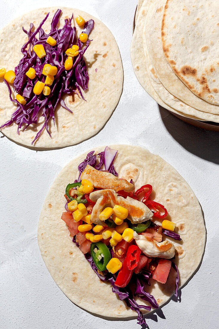 Homemade Mexican Tacos with fresh vegetables and chicken with strong light on white background. Healthy food. Typical Mexican