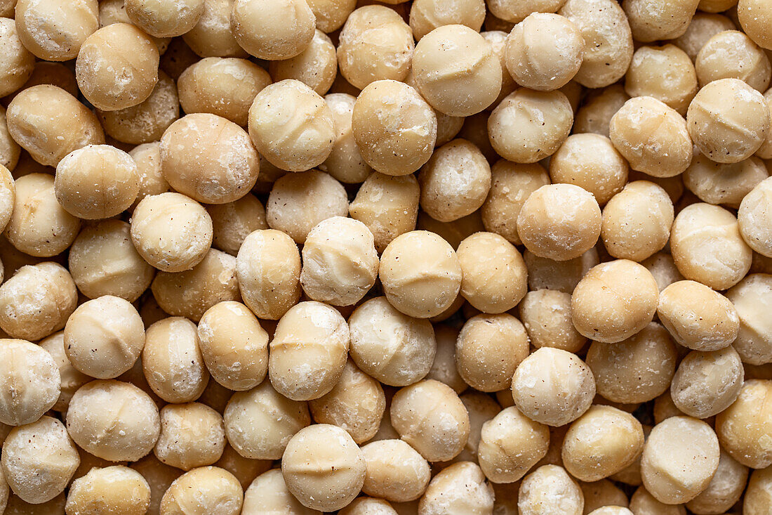 Full frame top view of scattered Macadamia Nuts in sugar powder placed on table