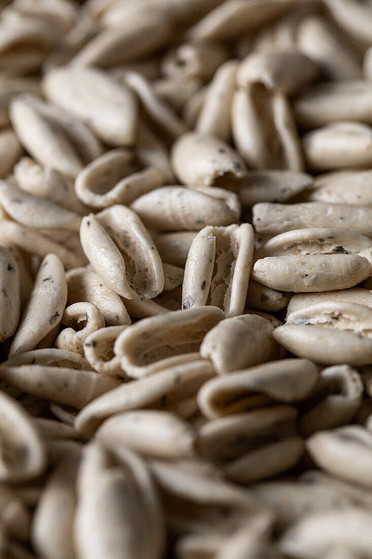 Full frame high angle of raw Basil cavatelli pasta scattered on smooth surface