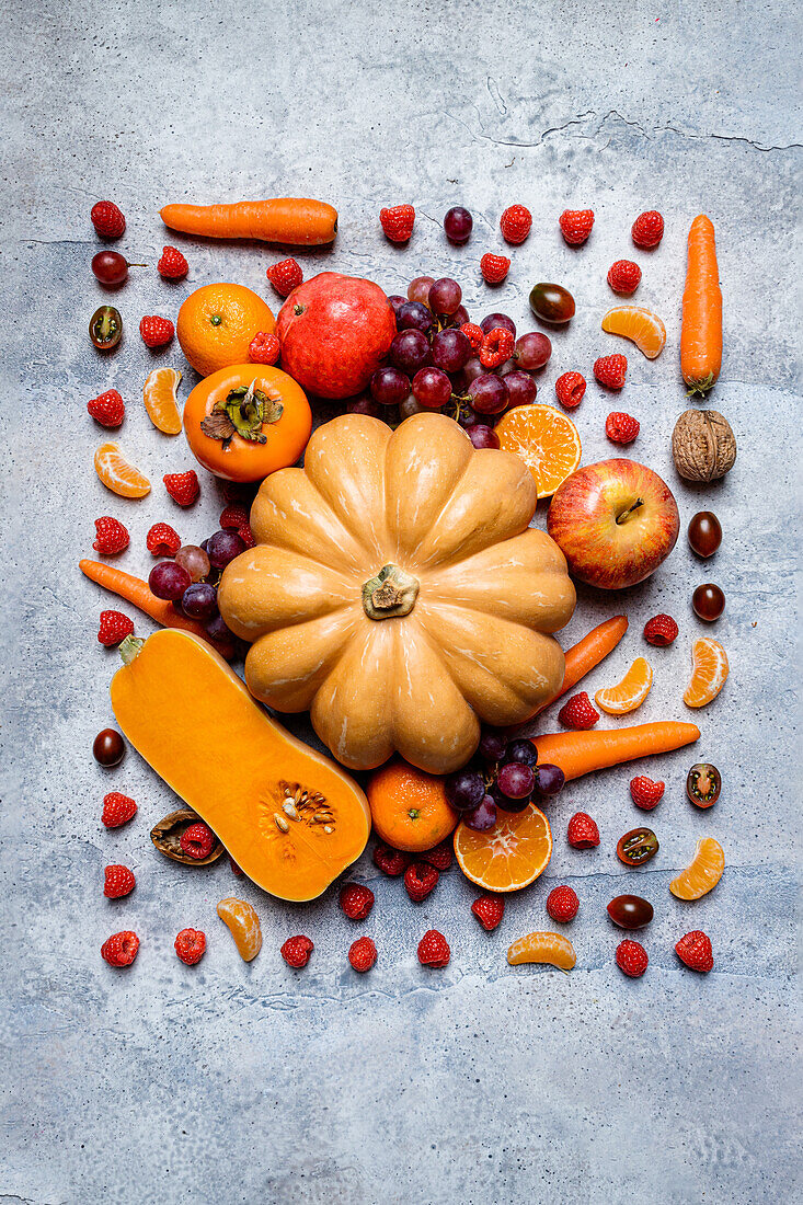 Stilleben mit verschiedenen Herbstgemüsesorten, Kürbissen, Äpfeln, Kaki, Mandarinen, Trauben und Haselnüssen von oben