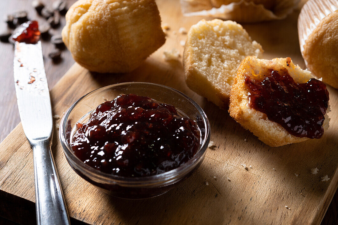 From above delicious homemade muffins and raspberry jam on wooden board on table