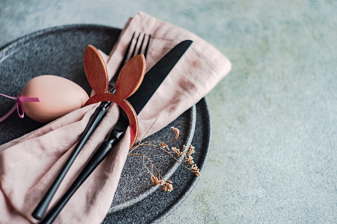 From above table set for Easter dinner with pink napkin and eggs on concrete background