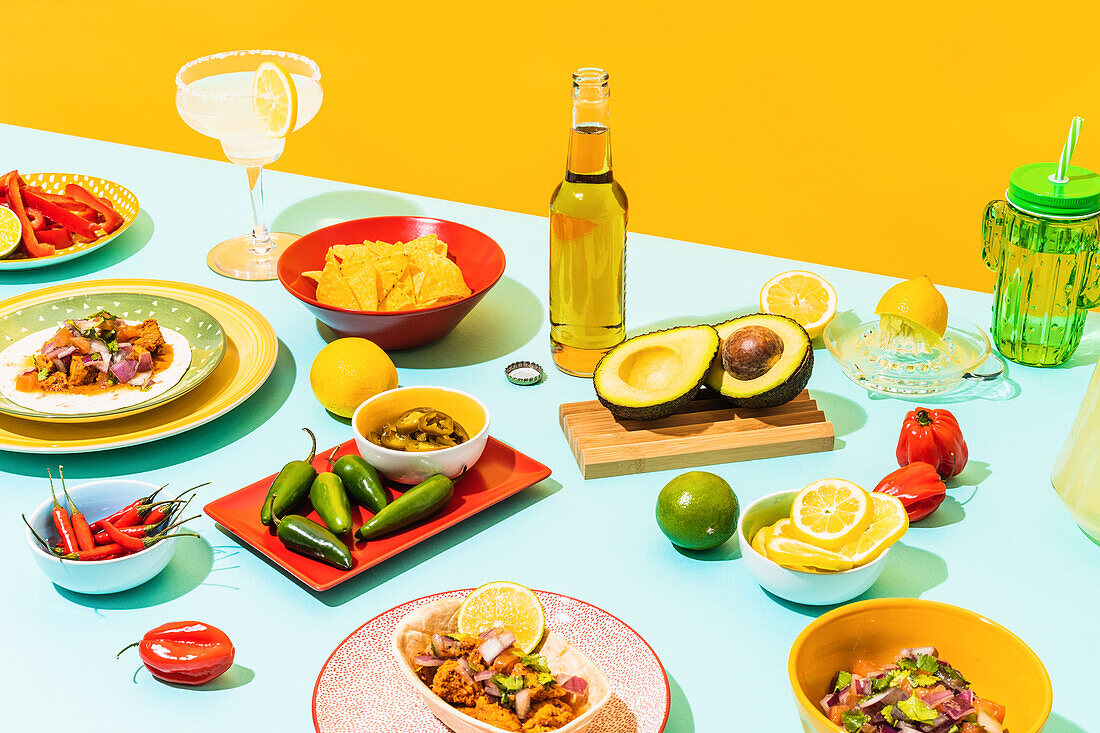 Verschiedene traditionelle mexikanische Gerichte und Getränke auf einem blauen Tisch an einer gelben Wand von oben