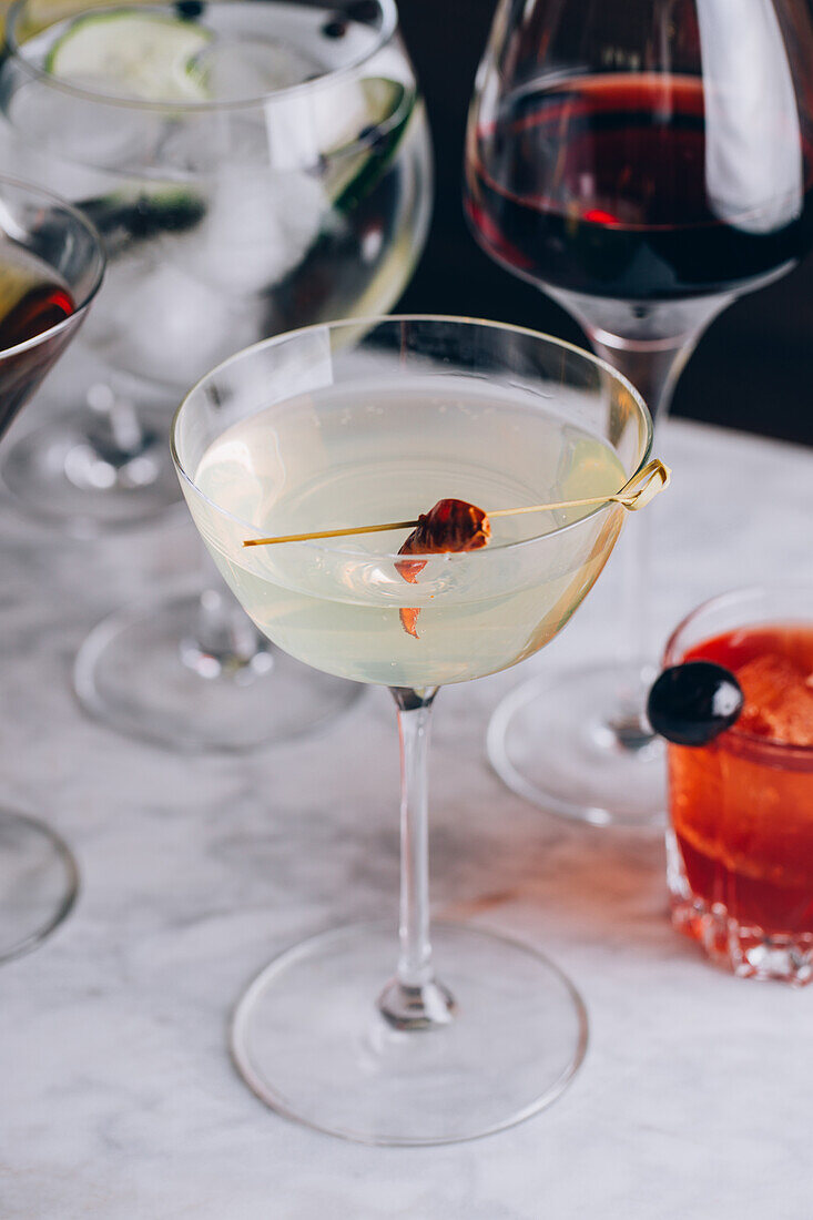 Glasbecher mit Martini-Cocktail, garniert mit rotem Pfeffer, serviert auf einem Tisch vor schwarzem Hintergrund, von oben