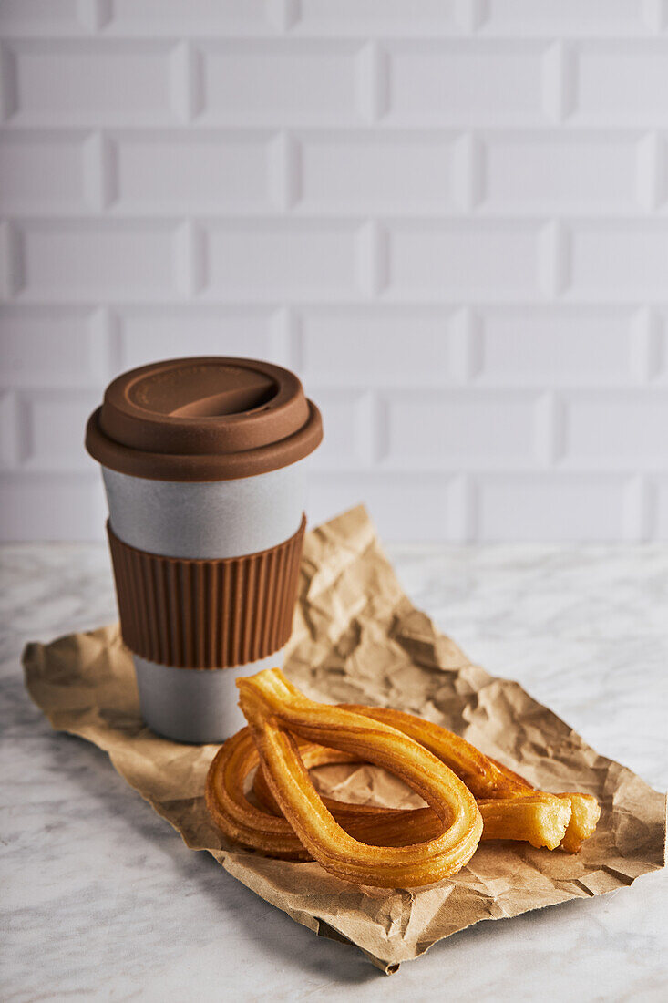 Fresh crispy churros and cup of hot coffee placed on table for breakfast