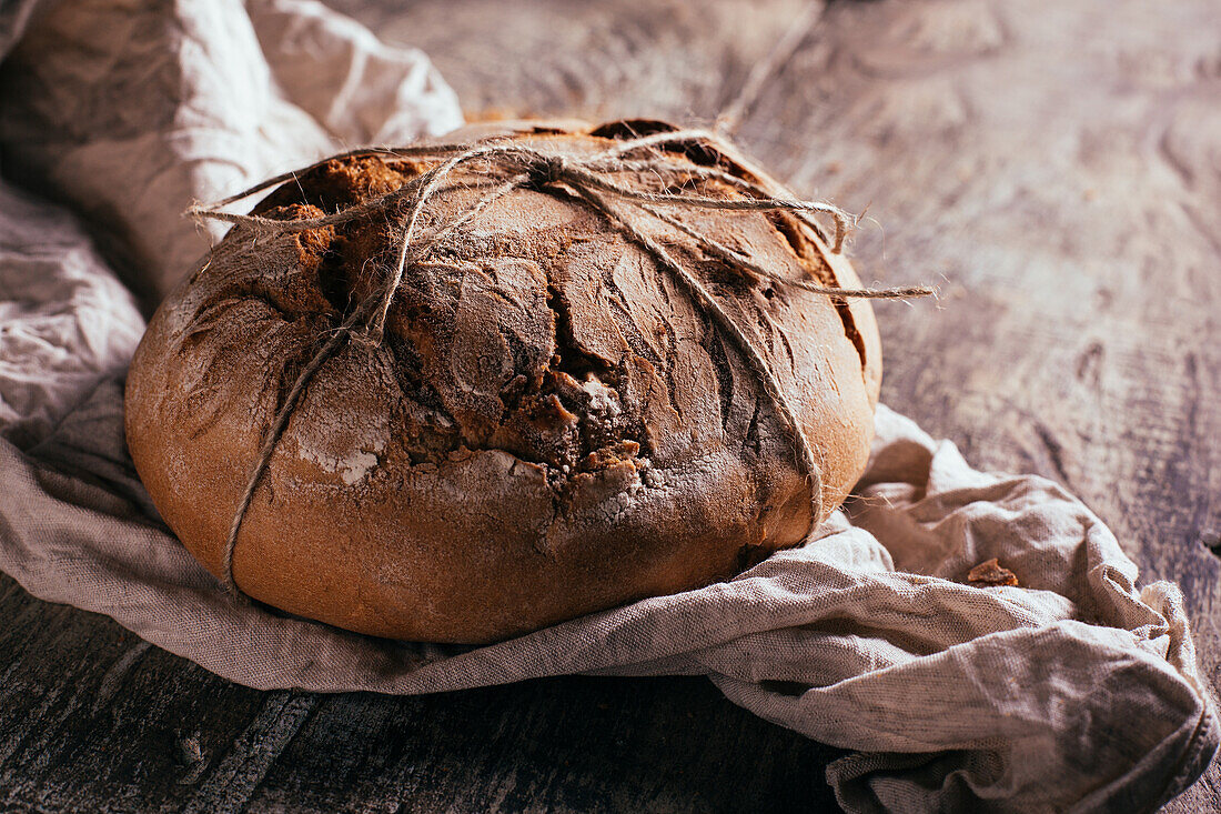 From above of delicious freshly baked bread placed on aged cutting board on wooden table in kitchen