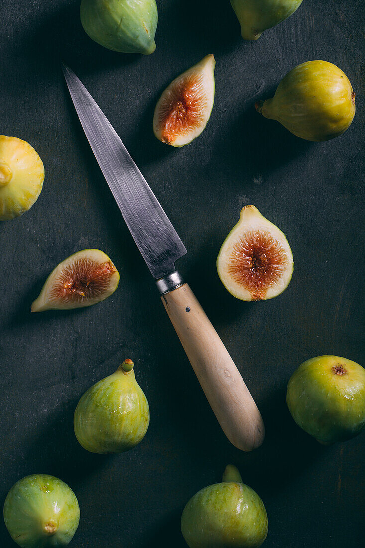 Top view of fresh sweet figs arranged with knife on dark background