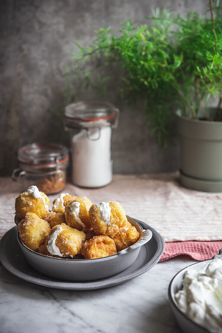 Bowl with crunchy nun's puffs bites stuffed with cream cheese placed on table in kitchen at home