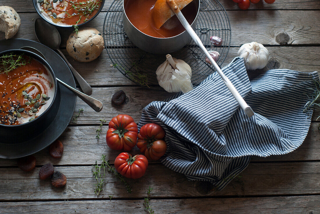 Flache Schalen mit cremiger Tomatensuppe, garniert mit Kernen und serviert auf einem Tisch mit Tomaten und getrockneten Aprikosen