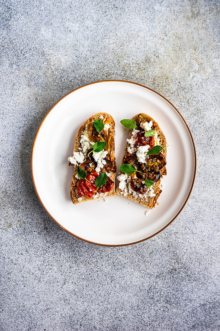 Sourdough bread toasts with cheese and roasted spiced tomato with oregano on the plate