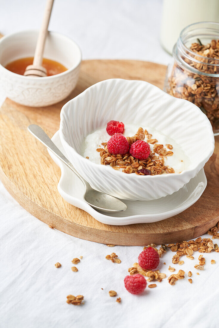 Tasty granola with sweet honey and fresh dairy product served for breakfast on wooden board