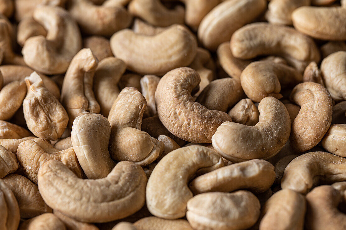 Vollbildansicht von oben einer großen Menge roher, schmackhafter Cashews auf glatter Oberfläche