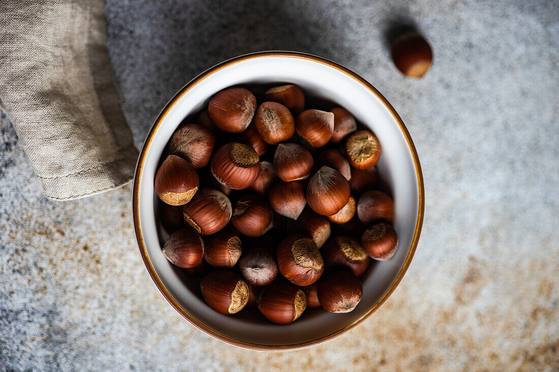 From above bowl full of tasty fresh hazelnut on concrete background