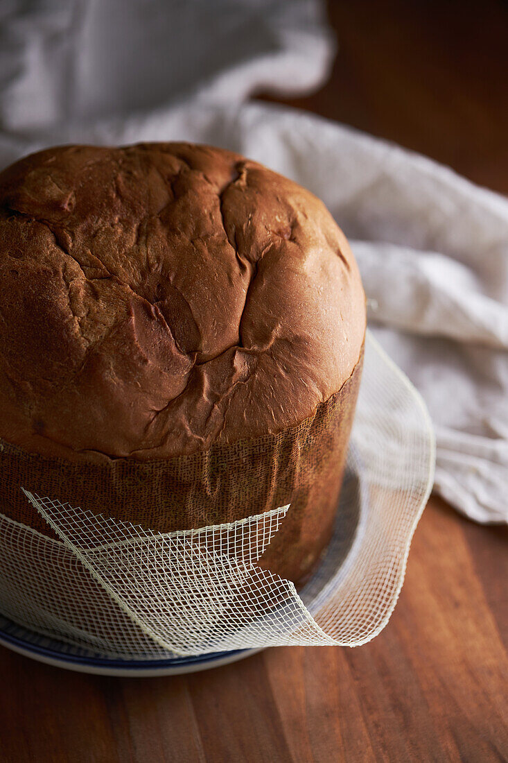 Hoher Winkel eines ungeschnittenen, frisch gebackenen, handwerklichen Weihnachts-Panettone-Kuchens auf einem Holztisch