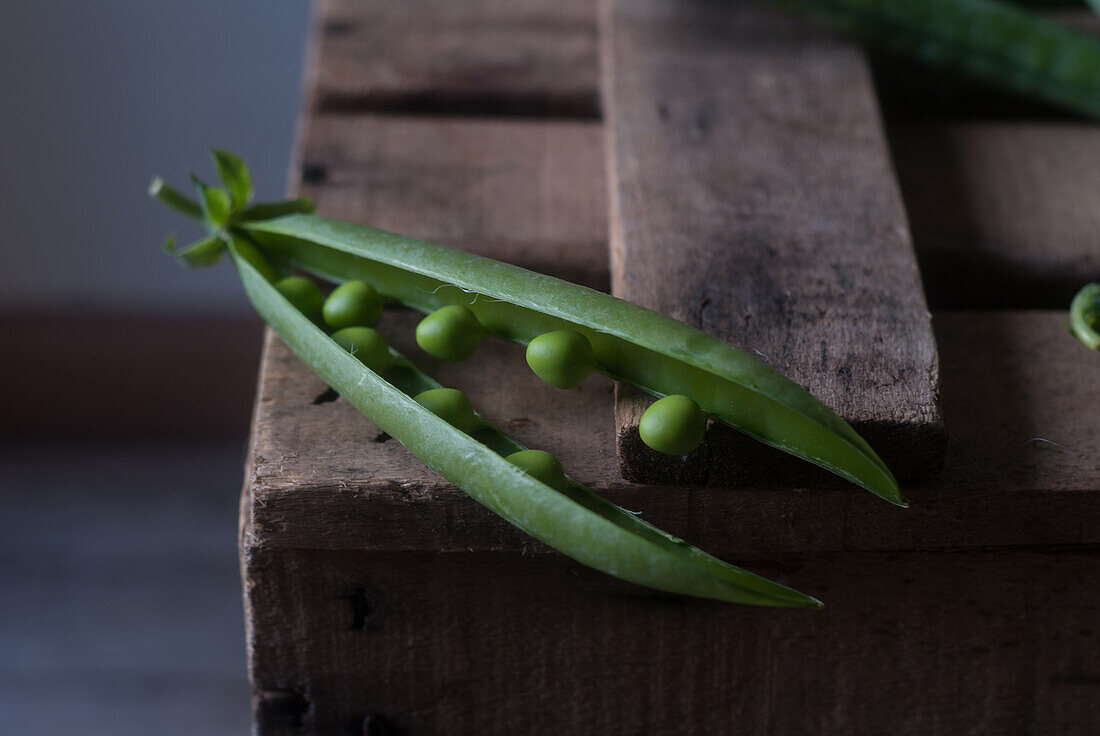 From above closeup view of fresh opened pod with shiny peas on wood