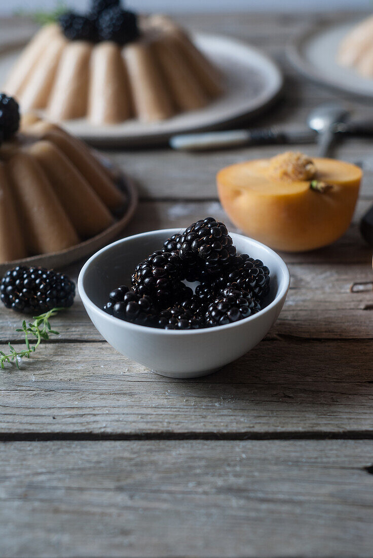 Nahaufnahme einer servierten veganen Panna Cotta mit Pfirsich und glänzenden süßen Brombeeren