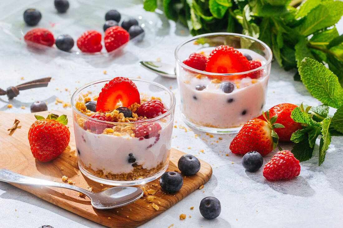 From above delicious homemade yogurt with strawberries, berries and cereals on white background