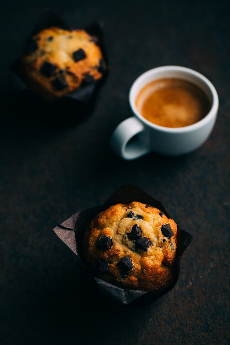 Chocolate muffins and coffee cup on dark background