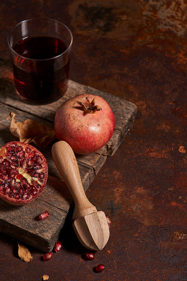 Frischer ganzer Granatapfel und Kerne von oben auf einem Holzbrett neben einer Presse