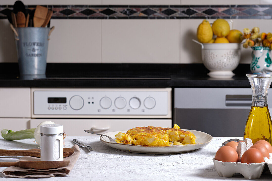 Appetizing traditional Spanish omelette placed on table with eggs and onion in domestic kitchen