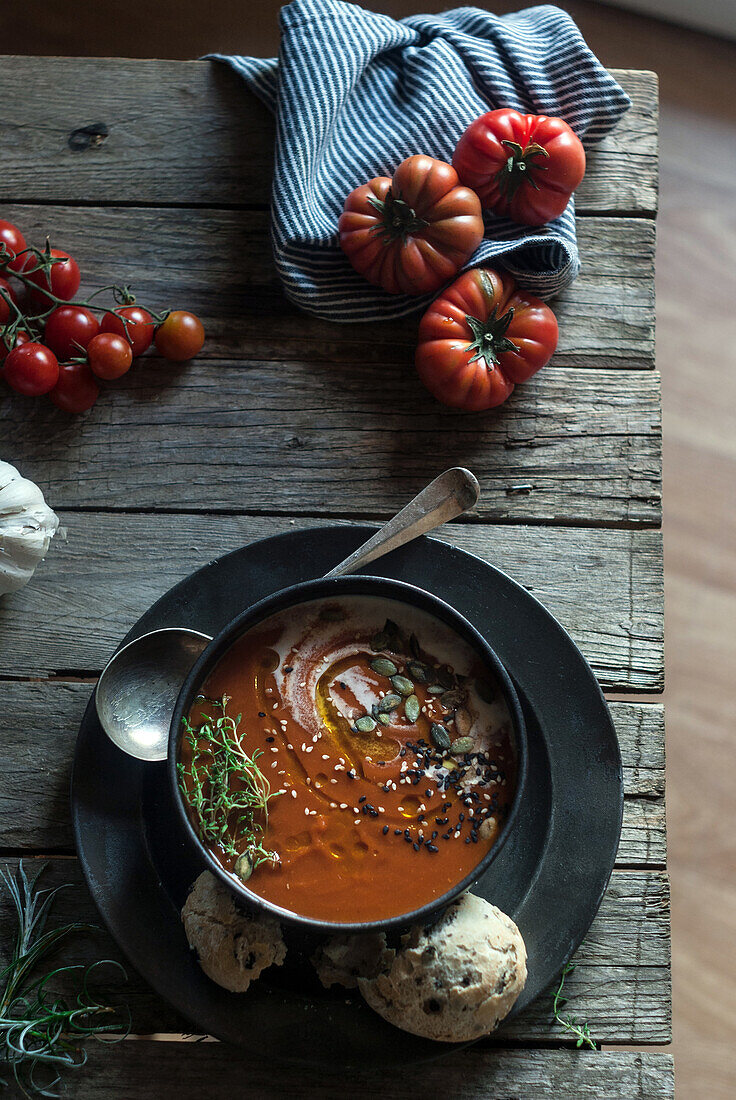 Flache Schalen mit cremiger Tomatensuppe, garniert mit Kernen und serviert auf einem Tisch mit Tomaten und getrockneten Aprikosen