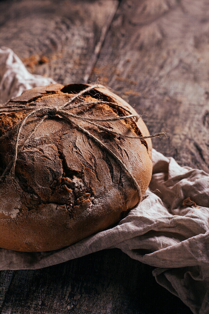 Köstliches frisch gebackenes Brot auf altem Schneidebrett auf einem Holztisch in der Küche von oben