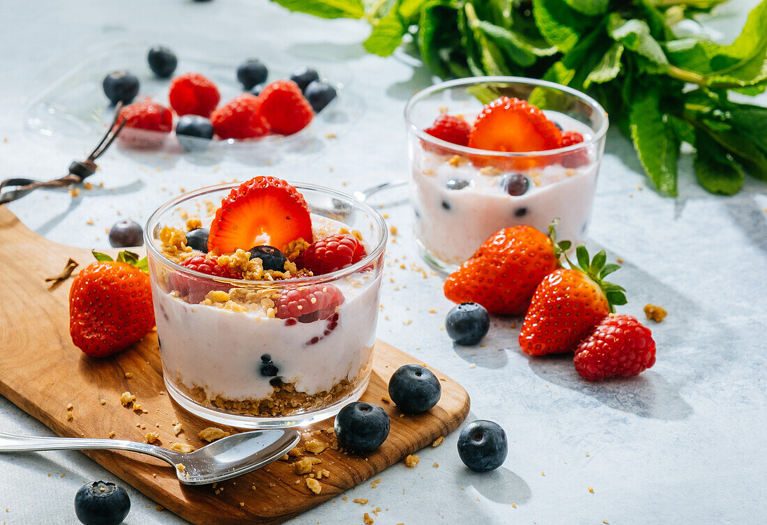 Von oben köstlicher hausgemachter Joghurt mit Erdbeeren, Beeren und Müsli auf weißem Hintergrund