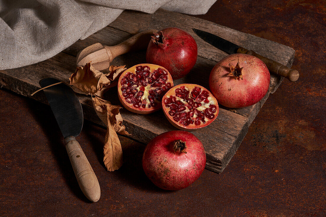 From above fresh whole pomegranate and seeds arranged on wooden board near squeezer