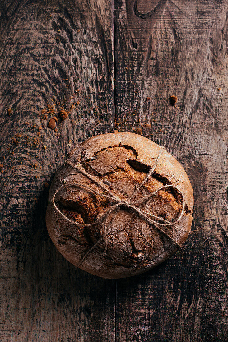 Top view of delicious freshly baked bread placed on aged cutting board on wooden table in kitchen
