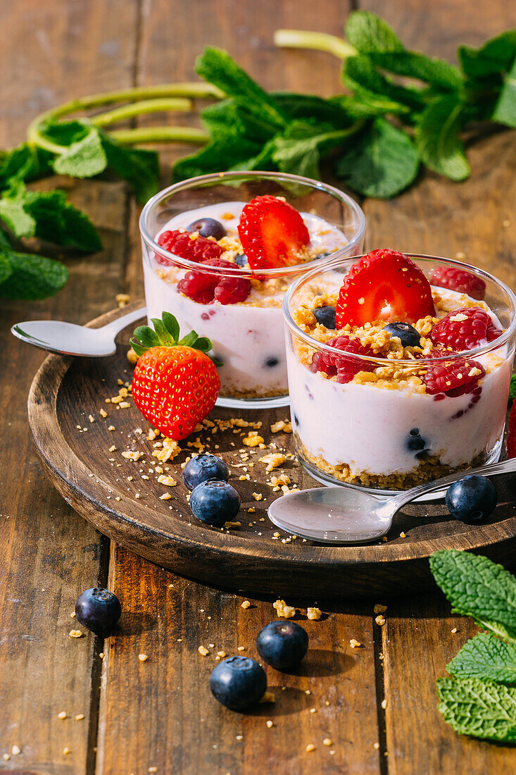 From above delicious homemade yogurt with strawberries, berries and cereals on wooden table background