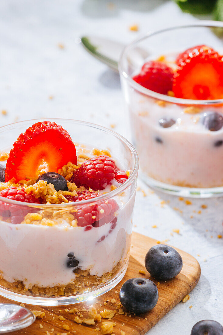 Nahaufnahme eines köstlichen hausgemachten Joghurts mit Erdbeeren, Beeren und Müsli auf weißem Hintergrund