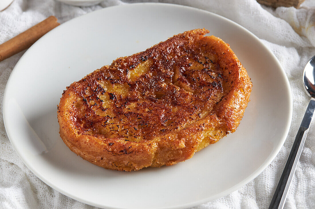 High angle of appetizing crispy torrija placed on plate and served on white wooden table spoon