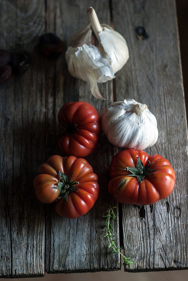 From above of ripe red tomatoes with white garlic bulbs composed on wooden table