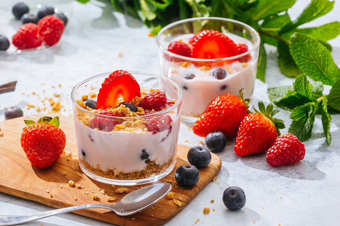 Von oben köstlicher hausgemachter Joghurt mit Erdbeeren, Beeren und Müsli auf weißem Hintergrund