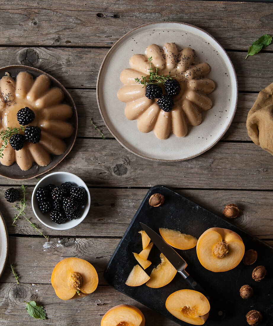 Flat lay of arranged served panna cotta with peach and poppy seeds on table with blackberry