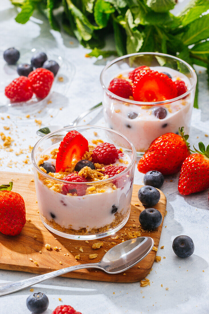 From above delicious homemade yogurt with strawberries, berries and cereals on white background