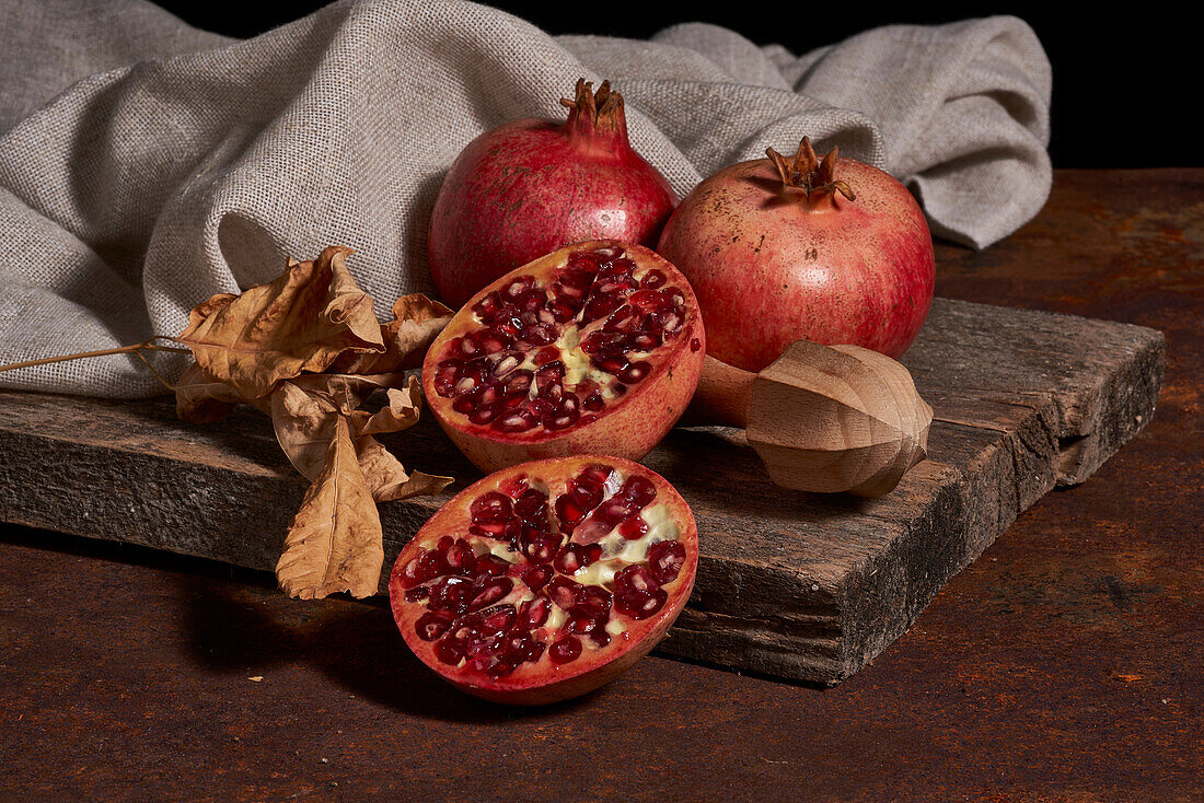 From above fresh whole pomegranate and seeds arranged on wooden board near squeezer