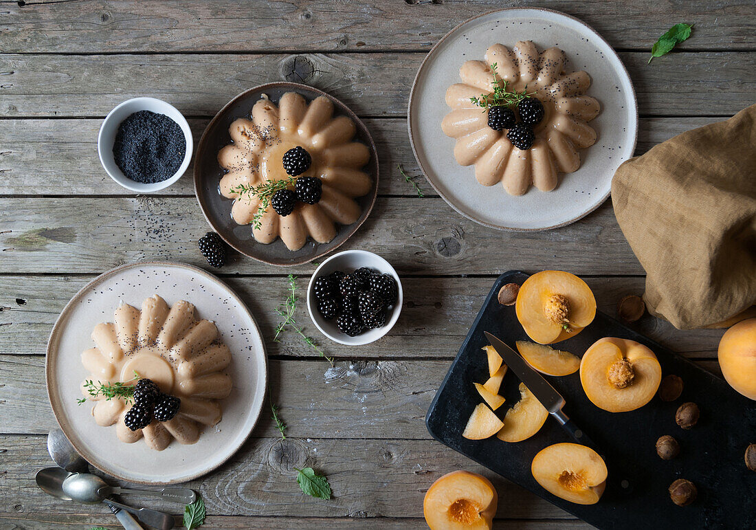 Flat lay of arranged served panna cotta with peach and poppy seeds on table with blackberry