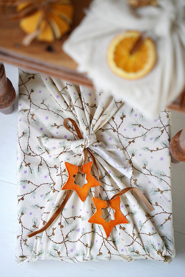 Geschenk in Stoffverpackung mit getrockneten Orangenscheiben und Sternanhängern aus Orangenschale